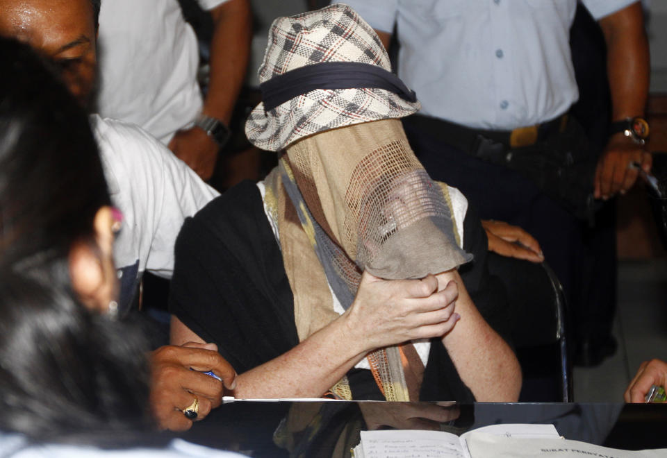 Australian Schapelle Corby, covering her face, gestures at the correctional office after she received her parole in Bali, Indonesia, Monday, Feb. 10, 2014. The Australian woman convicted of smuggling marijuana into Indonesia in 2005 has been released from jail on parole. She was convicted of smuggling 4.2 kilograms (9 pounds) of marijuana onto Bali and sentenced to 20 years in prison. (AP Photo/Firdia Lisnawati)