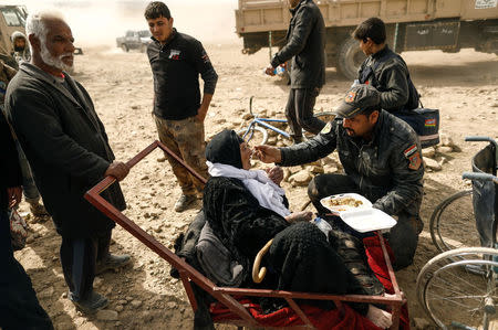 A special forces member feed a displaced Iraqi woman who just fled her home, as she waits to be transported while Iraqi forces battle with Islamic State militants in western Mosul, Iraq February 27, 2017. REUTERS/Zohra Bensemra