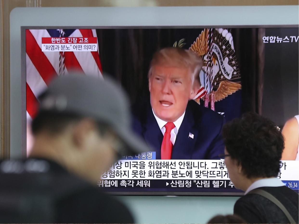 People walk by a TV screen showing a local news program reporting with an image of U.S. President Donald Trump at the Seoul Train Station in Seoul, South Korea on 9 Aug 2017: AP