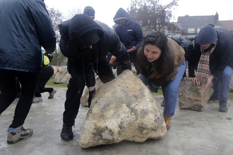 Activistas locales intentan retirar rocas colocadas por el ayuntamiento para evitar reuniones de inmigrantes en Calais, norte de Francia, el miércoles 8 de marzo de 2023. (AP/Michel Spingler)