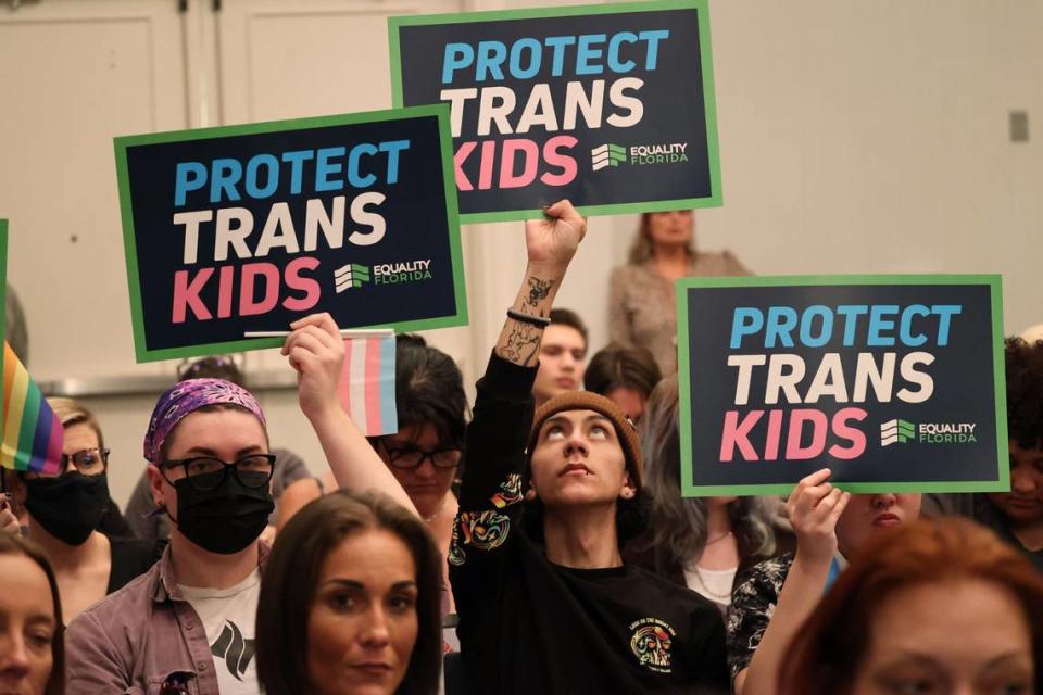 People hold signs during a joint board meeting of the Florida Board of Medicine and the Florida Board of Osteopathic Medicine, Friday, Nov. 4, 2022, in Lake Buena Vista, Fla., to establish new guidelines limiting gender-affirming care in Florida.