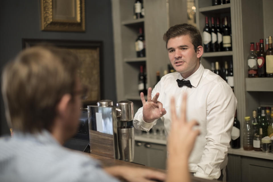 A bartender giving a customer the "okay" symbol.