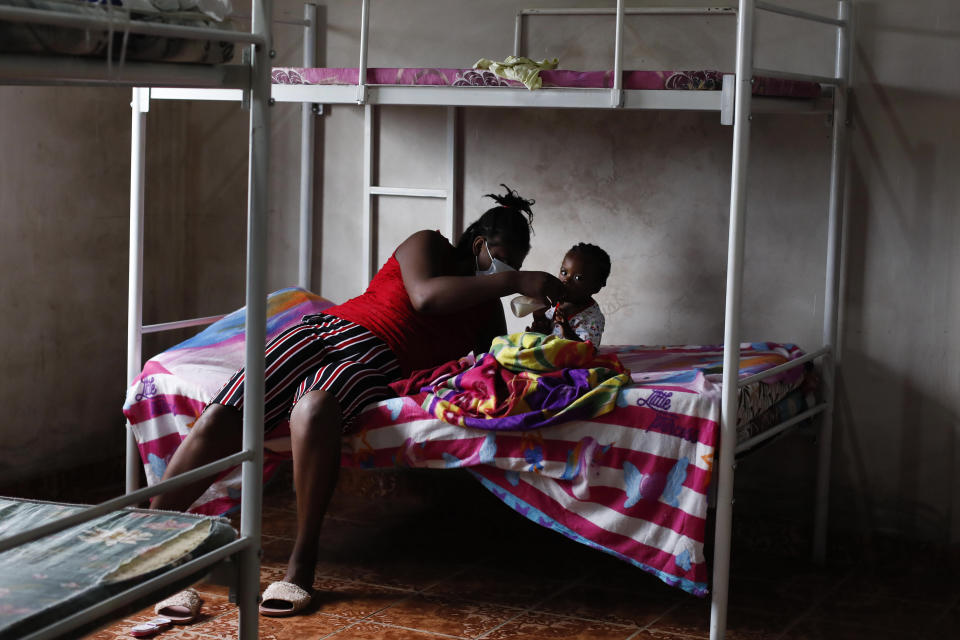 Haitian migrant Occeant Jesula bottle feeds her one-year-old son Jhony, at the Jesus Esta Vivo shelter in Danli, Honduras, Wednesday, Sept. 22, 2021. (AP Photo/Elmer Martinez)