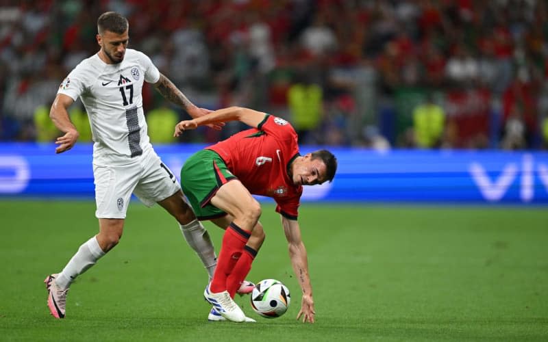 Jan Mlakar, da Eslovénia (à esquerda), e João Palhinha, de Portugal, lutam pela bola durante o jogo dos oitavos-de-final do UEFA Euro 2024 entre Portugal e Eslovénia, na Arena de Frankfurt.