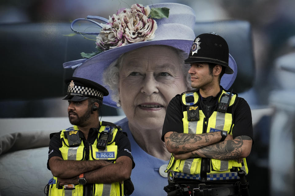 Police officers are backdropped by a photograph of Queen Elizabeth II in London, Friday, Sept.16, 2022. The Queen will lie in state in Westminster Hall for four full days before her funeral on Monday Sept. 19.(AP Photo/Vadim Ghirda)