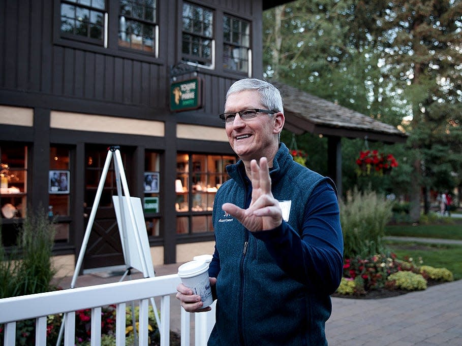 Tim Cook waving while walking with a coffee.