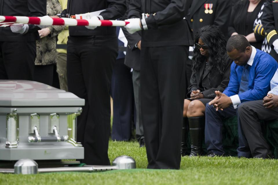 Sharon Blair, second from right, mother of U.S. Navy Petty Officer 2nd Class Mark Mayo, of Hagerstown, Md., bows her head during a burial service at Arlington National Cemetery in Arlington, Va., Friday, April 25, 2014. Mayo was killed aboard the USS Mahan at Naval Station Norfolk, Va., after he dove in front of another sailor to protect her from a civilian truck driver who had seized her gun. Mayo was awarded the Navy Marine Corps Medal, the highest non-combatant decoration for heroism by a sailor or Marine. (AP Photo/ Evan Vucci)