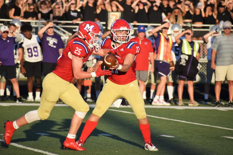 Martinsville's Tyler Adkins (17) and Brayden Shrake (25) meet on a hand-off during the Artesians' rivalry matchup with Bloomington South on Aug. 26, 2022.