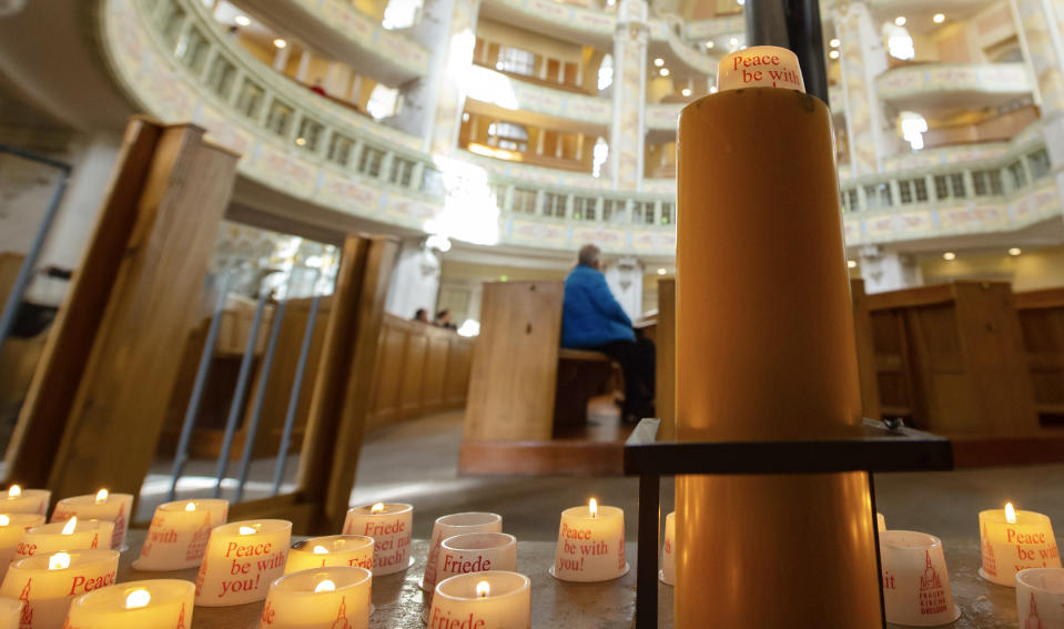 A visitor sits behind candles in the Frauenkirche cathedral (Church of Our Lady) in Dresden, Germany, Tuesday, Feb. 11, 2020 two days before the 75th anniversary of the Allied bombing of Dresden during WWII. British and U.S. bombers on Feb. 13-14, 1945 destroyed Dresden's centuries-old baroque city center. (AP Photo/Jens Meyer)