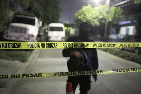 A policeman custodies a surrounding area of a prison where 14 members of the Barrio 18 group were killed in Quezaltepeque, El Salvador August 22, 2015. REUTERS/Jose Cabezas