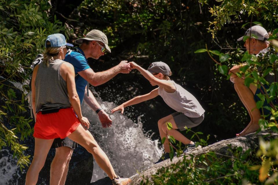 A family crossing over water and slippery rocks.