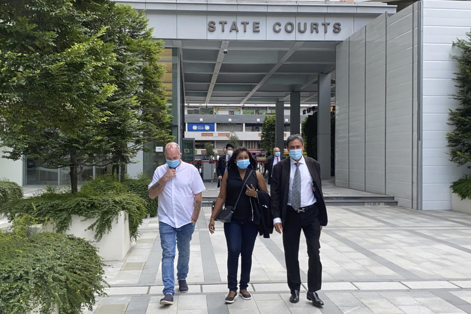 Skea Nigel, left, Agatha Maghesh Eyamalai, center, and defense lawyer Dhillon Surinder Singh leave the State Courts in Singapore, Monday, Feb. 15, 2021. Nigel, a British national, pleaded guilty on Monday to violating a coronavirus quarantine order in Singapore to visit his fiancee. (AP Photo/Annabelle Liang)