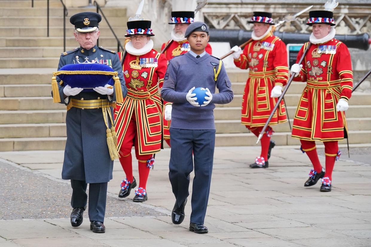 A member of the Royal Air Force Air Cadets, right, carries the Commonwealth of Nations' Globe as it arrives at the Tower of London, Thursday, April 14, 2022. The globe will be used in the lighting of the Principal Beacon at Buckingham Palace on June 2 and will be displayed for members of the public in the White Tower at the Tower of London until the Jubilee weekend.