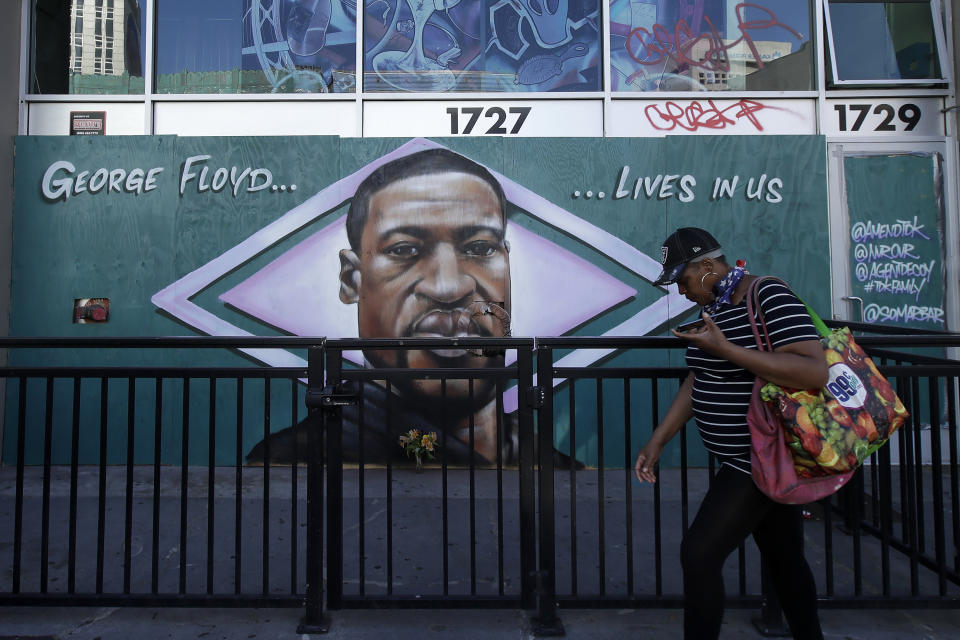 A person walks past a mural of George Floyd in Oakland, Calif., Thursday, June 4, 2020, as people protest over the death of George Floyd, who died May 25 after being restrained by police in Minneapolis. (AP Photo/Jeff Chiu)