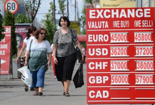 Pedestrians walk past an exchange office's rates notice in Bucharest August 10. The recovery in Romania's economy after two years of severe recession is now coming under threat, analysts warn, victim to the months-long political crisis that has engulfed the EU country