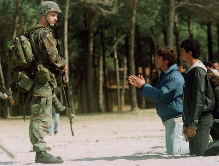 FILE PHOTO: An Albanian boy begs a U.S. Marine guarding a helicopter on the beach at Golame, March 16. The boy was one of hundreds of Albanian civilians who rushed to the helicopters in a vain bid to escape the country. The Sea Stallion choppers had been sent to evacuate U.S., Italian and Turkish nationals. REUTERS/Yannis Behrakis/File photo