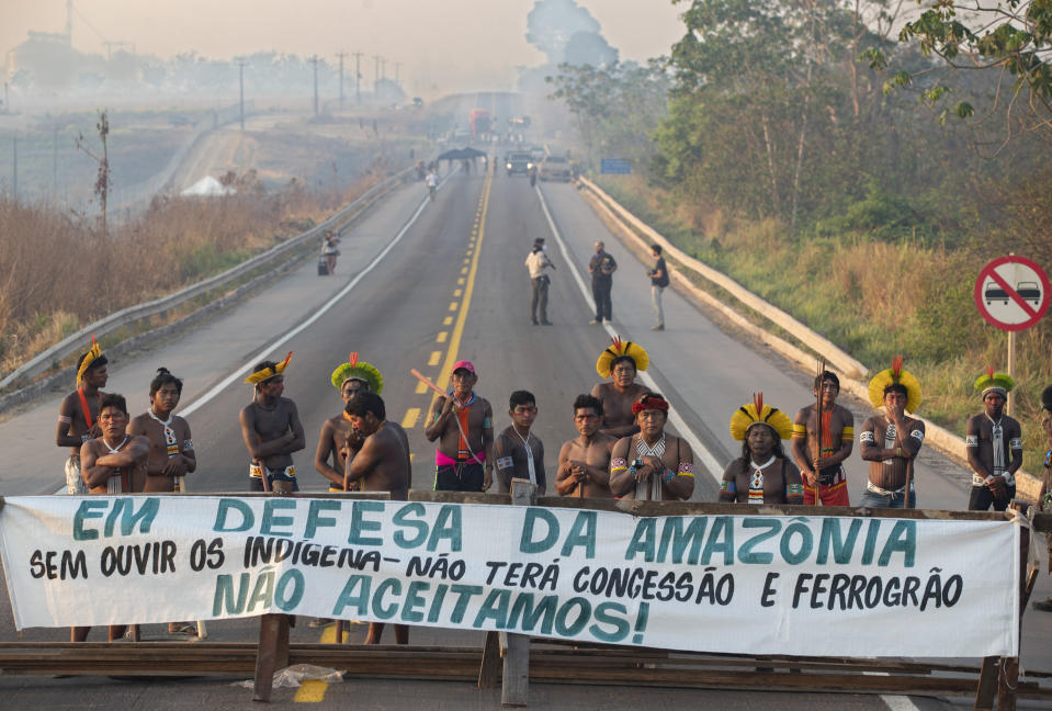 Kayapo Indigenous protesters block highway BR-163 with a banner that reads in Portuguese "Defending the Amazon. Without listening to Indigenous people, there will be no concession and nor grain railway," near Novo Progresso, Para state, Brazil, Monday, Aug. 17, 2020. Experts say blazes and deforestation are pushing the world's largest rainforest toward a tipping point, after which it will cease to generate enough rainfall to sustain itself. (AP Photo/Andre Penner)