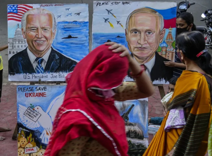 A woman adjusts her sari as she walks past as students of an art school display their art works calling for peace amid fears of a Russian offensive on Ukraine on a pavement in Mumbai, India, Monday, Feb. 21, 2022. (AP Photo/Rafiq Maqbool)