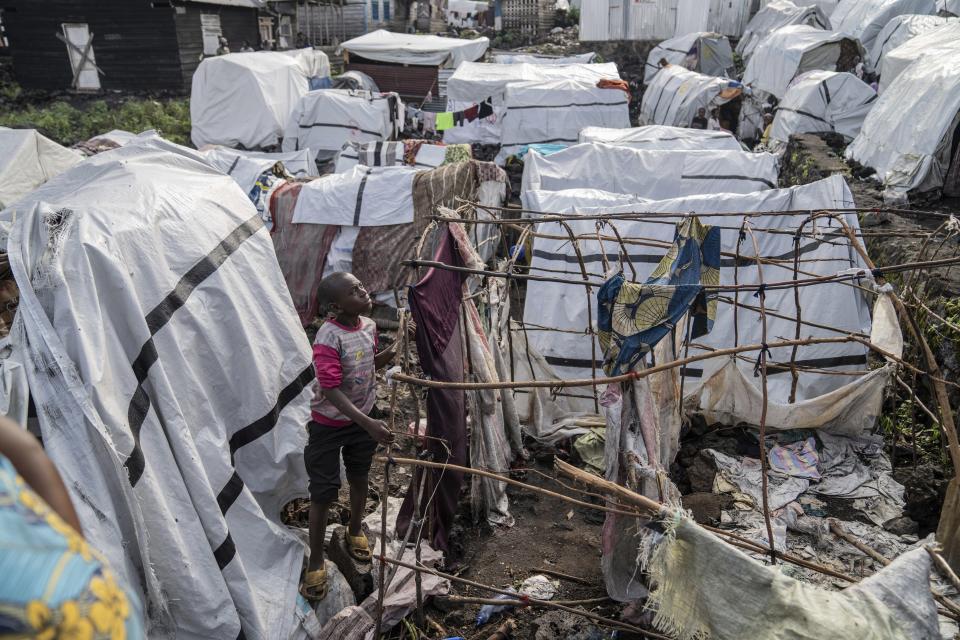 People gather at the side of an explosion in a refugee camp on the outskirts of Goma, Democratic Republic of the Congo, Friday, May, 3, 2024. The Congolese army says a bomb at a refugee camp in eastern Congo has killed at least 5 people, including children. An army spokesman blamed the attack at the Mugunga refugee camp in North Kivu on a rebel group, known as M23, with alleged links to Rwanda, in a statement provided to The Associated Press. (AP Photo/Moses Sawasawa)