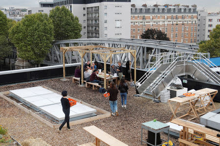 Poste office employees eat a lunch with products from a 900 square meters farm garden on the rooftop of their postal sorting center, as part of a project by Facteur Graine association to transform a city rooftop as a vegetable garden to grow fruits, vegetables, aromatic and medicinal plants, with also chickens and bees in Paris, France, September 22, 2017. Picture taken September 22, 2017. REUTERS/Charles Platiau