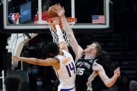 San Antonio Spurs center Jakob Poeltl (25) fouls Phoenix Suns guard Landry Shamet (14) as Shamet misses a dunk during the first half of an NBA basketball game Monday, Dec. 6, 2021, in Phoenix. (AP Photo/Ross D. Franklin)