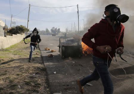 Palestinian protesters run during clashes with Israeli troops, following the funeral of Palestinian minister Ziad Abu Ein near the West Bank city of Ramallah December 11, 2014. REUTERS/Ammar Awad