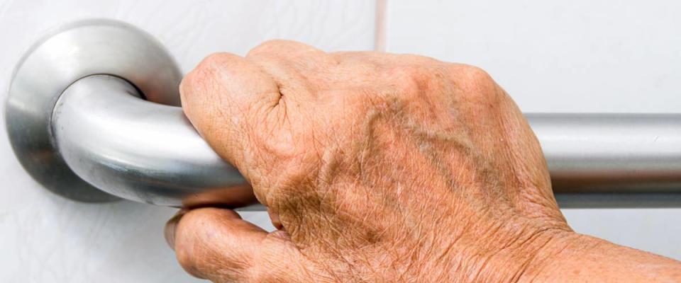 elderly holding a grab bars in a bathroom