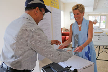 Ontario Premier Kathleen Wynne hands her ballot to an official at a polling station while voting in provincial election in Toronto, Ontario, Canada June 7, 2018. REUTERS/Chris Helgren