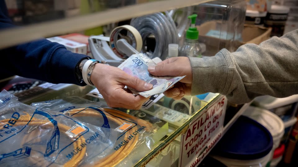 A worker receives Argentine peso banknotes in a shop in Buenos Aires on Sept. 26, 2023. Milei has proposed dollarizing Argentina. - Erica Canepa/Bloomberg/Getty Images