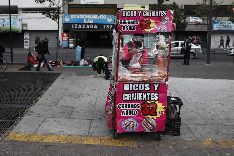 A vendor, wearing a protective face mask, is bundled up against the cold as she prepares churros in her mobile stall in Mexico City, Wednesday, Nov. 18, 2020, amid the new cornavirus pandemic. Mexico on Saturday topped 1 million registered COVID-19 cases and nearly 100,000 test-confirmed deaths, though officials agree the number is probably much higher. (AP Photo/Rebecca Blackwell)