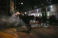 A demonstrator throws a tear gas canister back at riot police during a protest at the National University as a national strike continues in Bogota