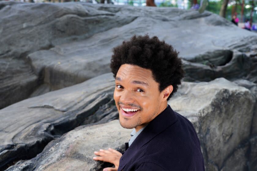 A smiling man poses in front of rocks