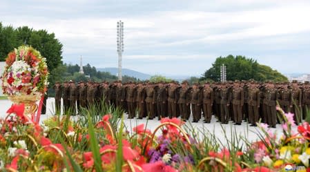 North Korean soldiers salute near floral tributes in North Korea