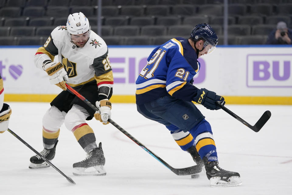 Vegas Golden Knights' William Carrier (28) reaches for the puck as St. Louis Blues' Tyler Bozak (21) skates past during the second period of an NHL hockey game Wednesday, April 7, 2021, in St. Louis. (AP Photo/Jeff Roberson)