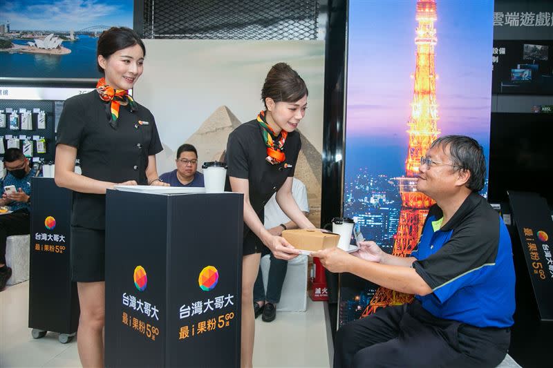 台灣大將iPhone 15開賣活動現場布置出國度假風，model扮演空服員送餐給果粉。（圖／台灣大提供）