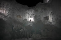 A tourist walks down the steps of an ice castle at the Lake Shikotsu Ice Festival in Chitose, Hokkaido, Japan, Feb. 6, 2020. After two months of almost no snow, Japan's northern city of Sapporo was overwhelmed with the white stuff. (AP Photo/Jae C. Hong)