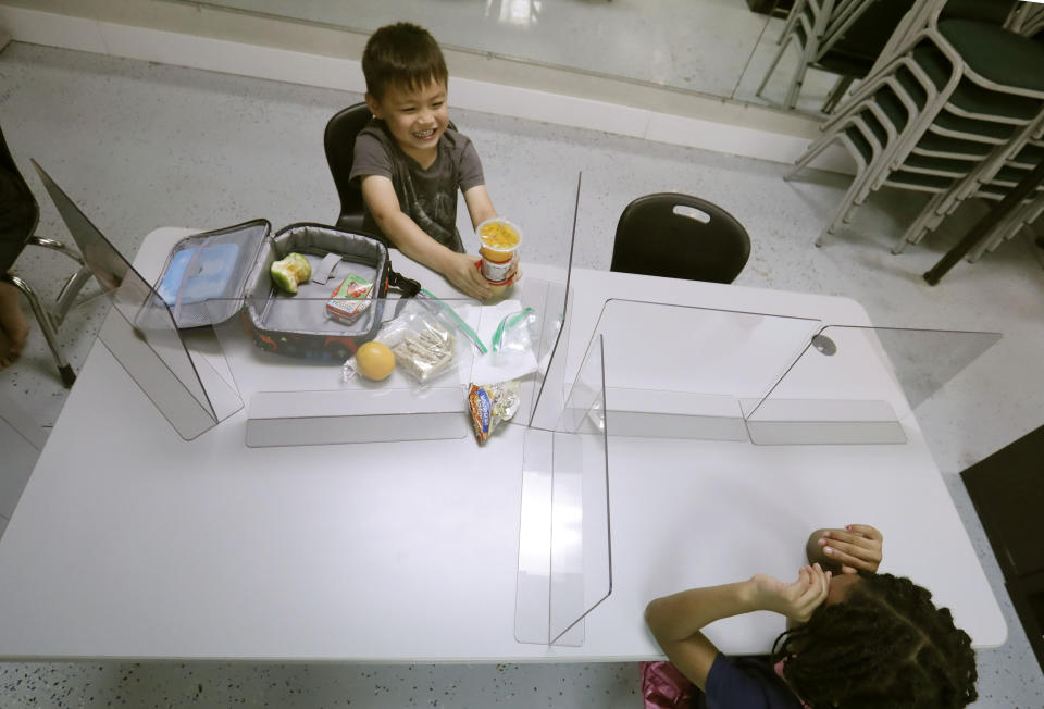 Plastic barriers are placed between Bruce McCall, 5, left, and Capri Bishop, 6, as they sit at a table during martial arts daycare summer camp at Legendary Blackbelt Academy in Richardson, Texas, Tuesday, May 19, 2020. As daycare and youth camps re-open in Texas, operators are following appropriate safety measure to insure kids stay safe from COVID-19. (AP Photo/LM Otero)