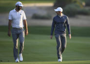 FILE - In this Jan. 18, 2018, file photo, Dustin Johnson of the United States, left, and Rory McIlroy of Northern Ireland talk on the 10th fairway during the first round of the Abu Dhabi Championship golf tournament in Abu Dhabi, United Arab Emirates. Dustin Johnson left The Players Championship two months ago and didn't play golf again until Sunday. He figured his game needed to be in shape for Rory McIlroy, his partner, in a charity match Sunday at Seminole that will be live golf's return to television. (AP Photo/Kamran Jebreili, File)