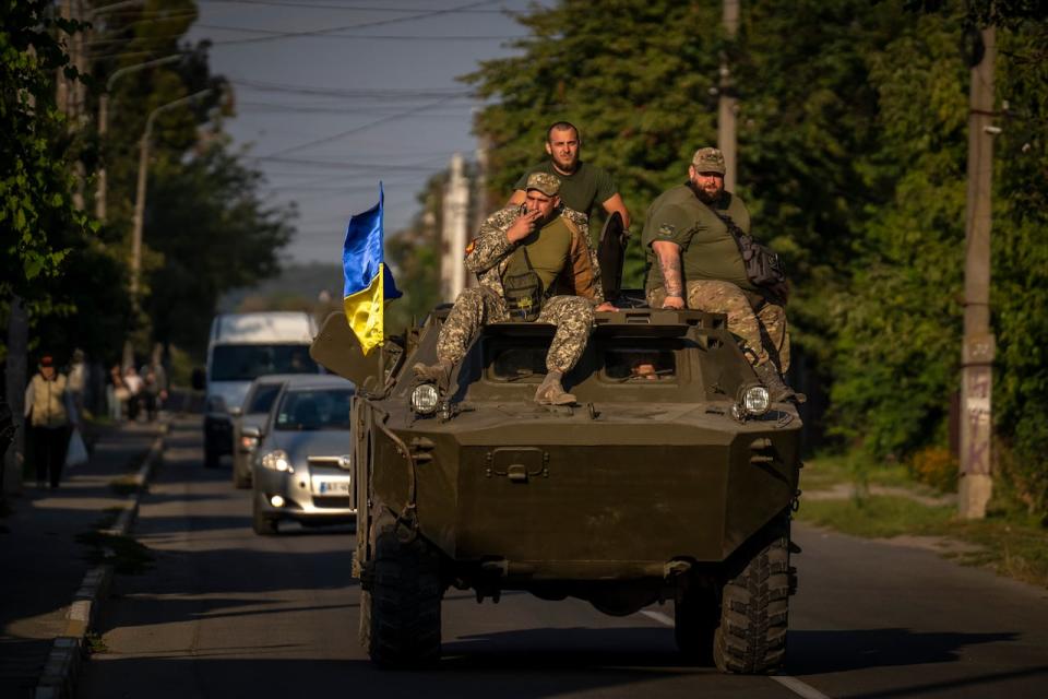 Ukrainian army soldiers sit on an armoured military vehicle as they drive in Bucha, near in Kyiv, Ukraine, Thursday, Sept. 8, 2022.