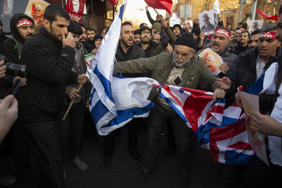 TEHRAN, IRAN - JANUARY 12: Protesters chant slogans and hold up posters of Gen. Qassem Soleimani while preparing to burn representations of British and Israeli flags, during a demonstration in front of the British Embassy on January 12, 2020 in Tehran, Iran. A candlelight vigil held late on Saturday in Tehran, to remember the victims of the Ukrainian plane crash, turned into a protest with hundreds of people chanting against the country's leaders including Supreme Leader Ayatollah Ali Khamenei and police dispersing them with tear gas. Police briefly detained the British ambassador to Iran, Rob Macaire, who said he went to the Saturday vigil without knowing it would turn into a protest.  (Photo by Majid Saeedi/Getty Images)