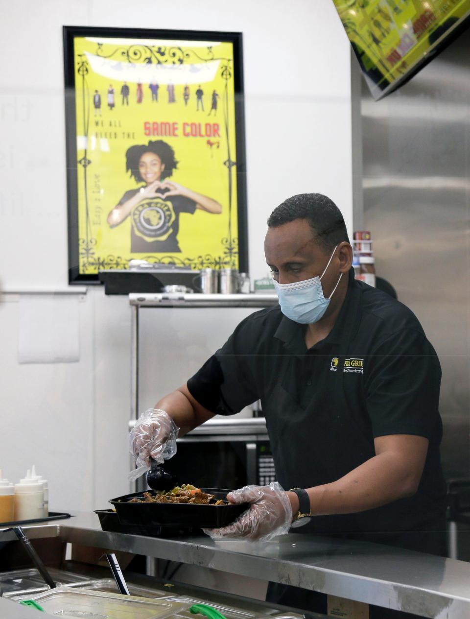 Owner Abdirahman "Abcos" Ahmed serves customers at his resaurant Afra Grill.