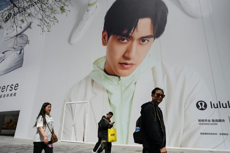 People walk past a billboard showing Chinese Formula One driver Zhou Guanyu at a shopping mall complex in Beijing (Jade GAO)