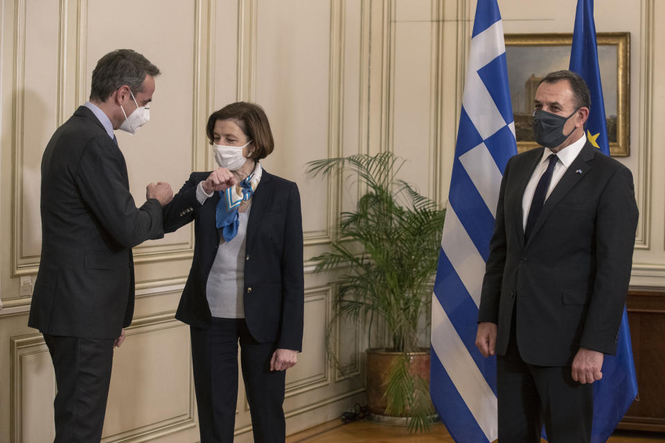 Greek Prime Minister Kyriakos Mitsotakis, left, welcomes French Defense Minister Florence Parly, centre, as Greek Defence Minister Nikos Panagiotopoulos looks on, during their meeting in Athens on Monday Jan. 25, 2021. Greece signed a 2.3 billion euro ($2.8 billion) deal with France Monday to purchase 18 Rafale fighter jets to address tension with neighbor Turkey. (AP Photo/Petros Giannakouris)