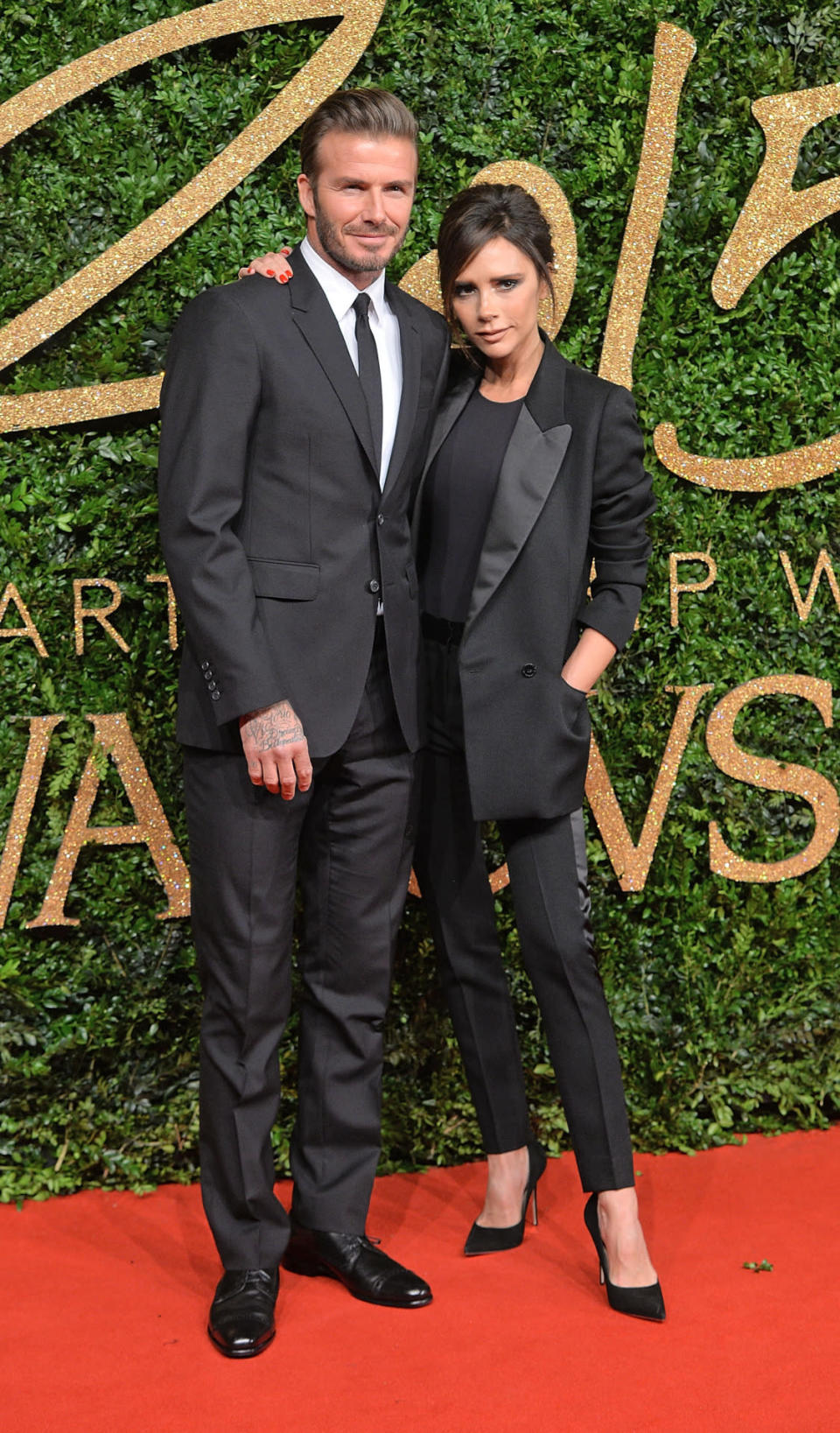 David and Victoria Beckham in a black tuxedo-style suit. 