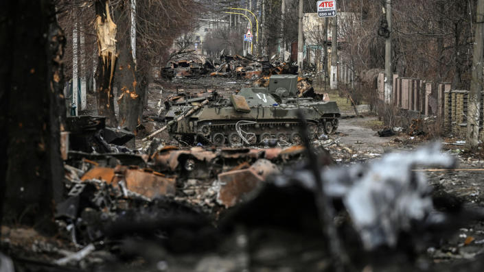 Destroyed Russian armored vehicles along a rubble-strewn road.