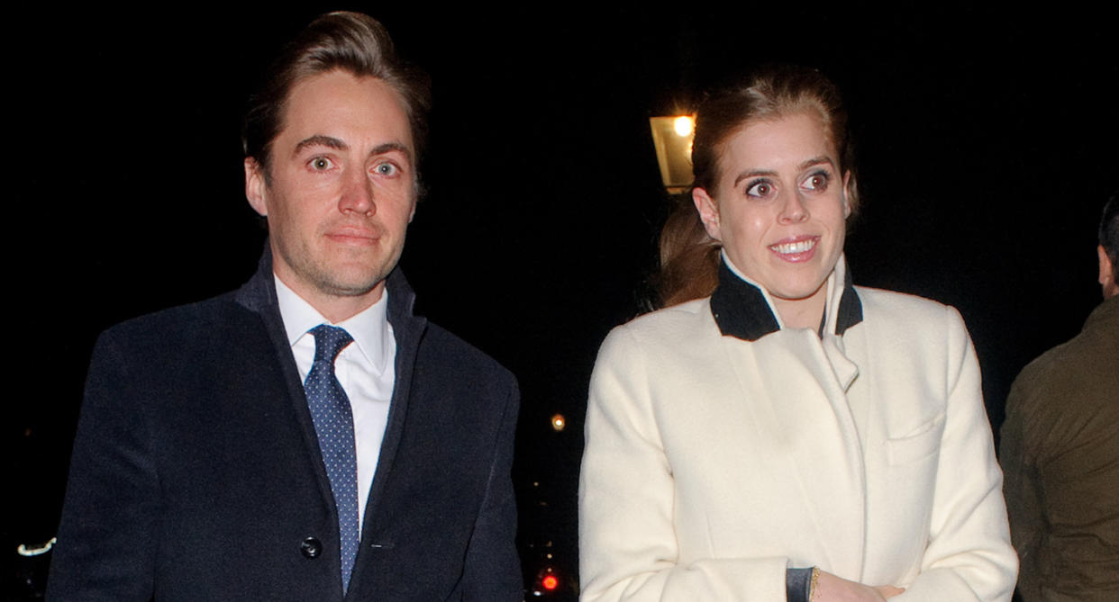 Princess Beatrice dressed in a white coat with a black collar walking at night with her fiance Edoardo Mapello Mozzi