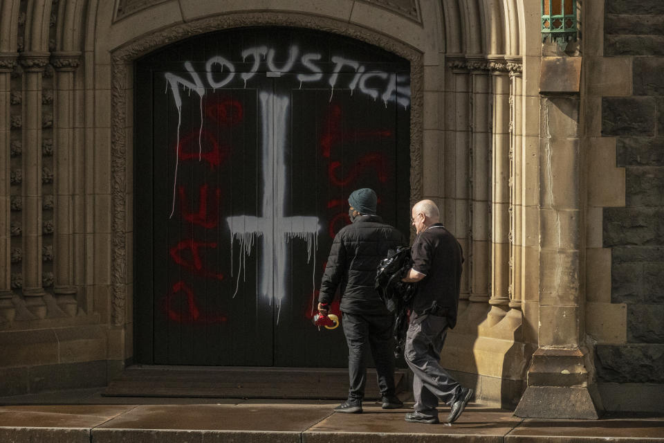 Picture of workers at the cathedral doors, where the doors read "No justice" and "rapist"