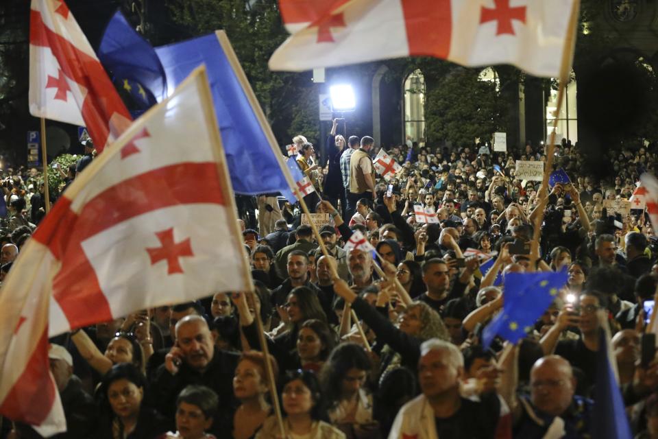 Demonstrators wave Georgian and EU flags as they gather outside the parliament building in Tbilisi, Georgia, on Wednesday, April 17, 2024, to protest against "the Russian law" similar to a law that Russia uses to stigmatize independent news media and organizations seen as being at odds with the Kremlin. (AP Photo/Zurab Tsertsvadze)