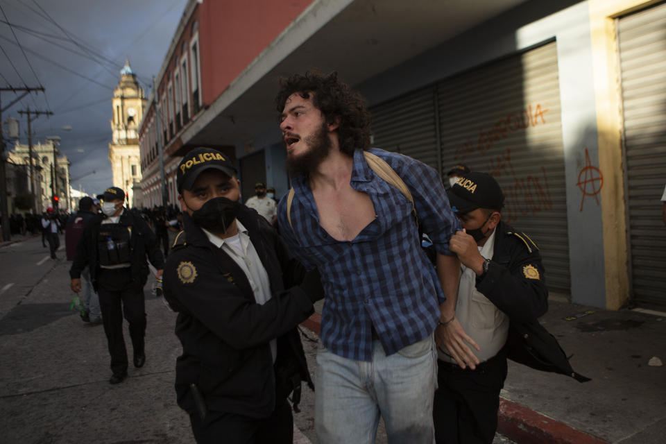 A man is detained by police near the Congress building after protesters set a part of the building on fire, in Guatemala City, Saturday, Nov. 21, 2020. Hundreds of protesters were protesting in various parts of the country Saturday against Guatemalan President Alejandro Giammattei and members of Congress for the approval of the 2021 budget that reduced funds for education, health and the fight for human rights. (AP Photo/Oliver De Ros)