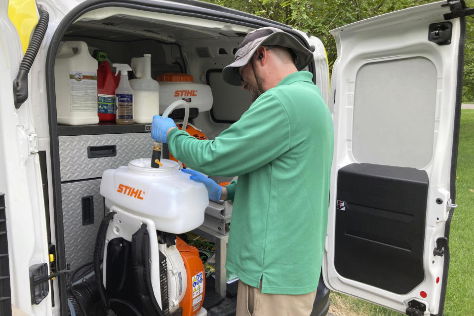 Mosquito Joe training technician Michael Kraft mixes essential oil insecticides to spray a yard in Cascade Township near Grand Rapids, Mich., July 20, 2022. As climate change widens the insect's range and lengthens its prime season, more Americans are resorting to the booming industry of professional extermination. But the chemical bombardment worries scientists who fear over-use of pesticides is harming pollinators and worsening a growing threat to birds that eat insects. (AP Photo/John Flesher)